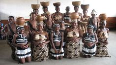 a group of people standing next to each other in front of a wall with vases on their heads