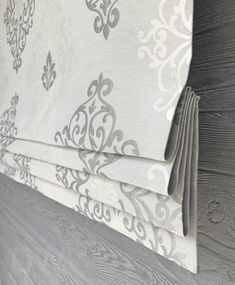 a close up view of the side of a bed with grey and white wallpaper