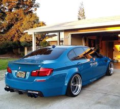 a blue car is parked in front of a garage with its door open and it's hood up