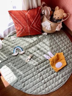 a stuffed animal sitting on top of a bed next to pillows and other items in a basket