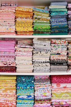 the shelves are filled with many different fabrics and fabric samples, all stacked on top of each other