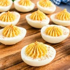 deviled eggs with mustard spread on them sitting on a cutting board