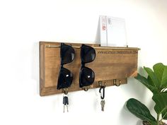 two pairs of sunglasses are hanging on a wooden shelf with keys and keychains