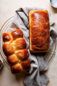 two loaves of bread sitting on top of a wire rack next to a napkin