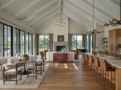 a large open concept kitchen and dining room with wood flooring, white walls and vaulted ceiling