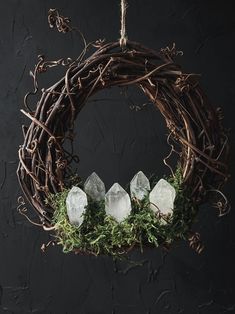 a wreath with crystals hanging from it's side and moss growing on the front