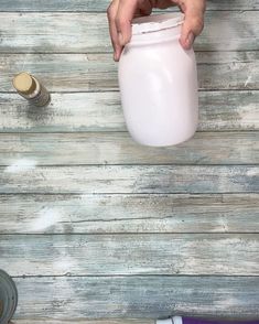 a person is holding a white container over a table