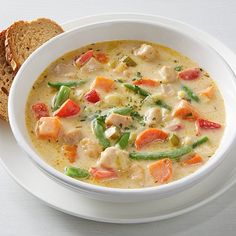 a white bowl filled with soup next to a slice of bread