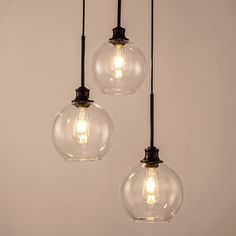 three clear glass globe pendant lights hanging from a ceiling