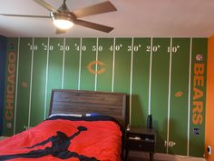 a bedroom decorated in green and orange with a football theme on the wall behind the bed