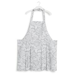 an apron that is on a hanger and has a white flower pattern in it