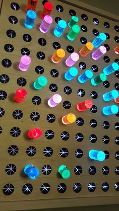 several different colored buttons on a wooden board with holes in the middle that are connected to each other