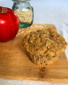 an apple and oatmeal muffin on a cutting board next to a jar of granola