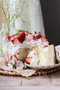 a cake with strawberries and whipped cream on top is sitting on a wicker platter