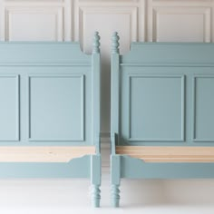 two blue beds side by side with wooden slats on the headboard and foot boards