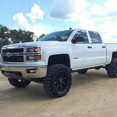 a white truck parked on top of a dirt field