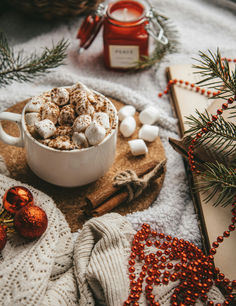 hot chocolate and marshmallows in a white bowl on a wooden board surrounded by christmas decorations