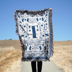 a person walking down a path with a blanket over their head that has the letter t on it