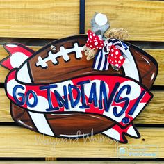 a wooden sign that says go indiana with a football on it and a bow in the middle