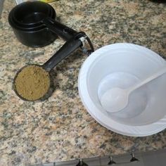 there is a bowl and spoon on the counter next to a measuring cup with some brown stuff in it