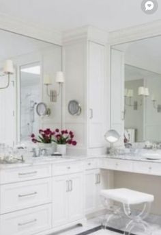 a white bathroom with two sinks, mirrors and stool in front of the mirror on the wall