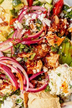 a salad with chicken, onions, cucumbers and feta cheese on it