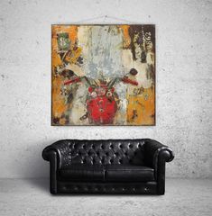 a black leather couch sitting in front of a wall with a painting hanging on it