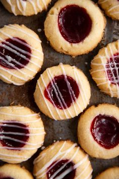 cookies with white icing and raspberry toppings on a baking sheet, ready to be eaten