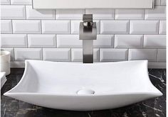 a white square sink sitting on top of a black and white tiled wall next to a faucet