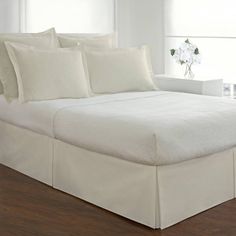 a bed with white sheets and pillows in a room