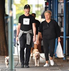 a man and woman walking their dog down the street