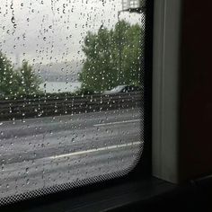 rain drops on the window as cars drive down the road in front of them,