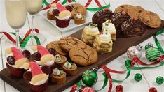 an assortment of cookies and desserts on a wooden platter next to wine glasses