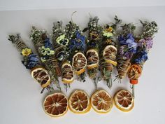 an arrangement of dried flowers and fruit arranged on a white surface with one cut in half