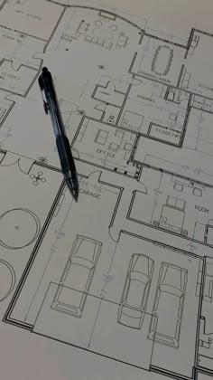 a pen sitting on top of a blueprinted floor plan with drawings in the background