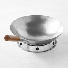 a metal pan with a wooden handle sitting on top of a white countertop next to a knife