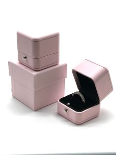 three pink jewelry boxes with one open and the other closed, on a white surface