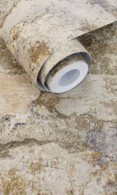 a roll of cement sitting on the ground next to a piece of concrete that has been chipped off