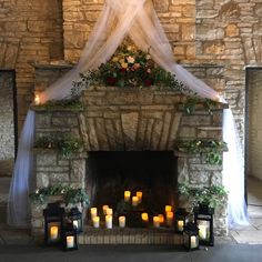 candles are lit in front of a stone fireplace