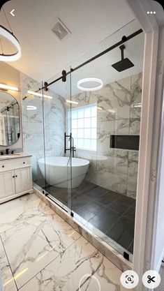 a bathroom with marble flooring and walls, glass shower door, and large bathtub