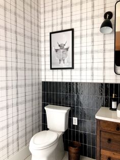 a white toilet sitting in a bathroom next to a wooden dresser and framed photograph on the wall