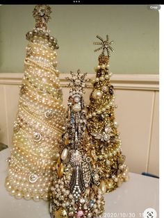 three small christmas trees made out of pearls and other beads on top of a table