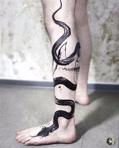 a man's leg with a black snake tattoo on it and his legs crossed