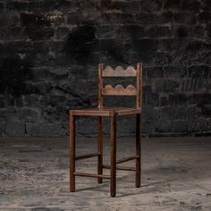 an old wooden chair sitting in front of a brick wall with a scalloped back and seat