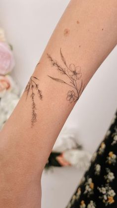 a woman's arm with a flower tattoo on the left side of her arm