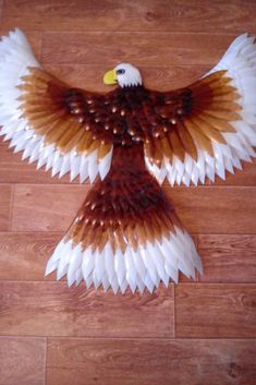 an eagle made out of paper sitting on top of a wooden floor