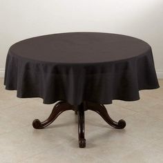 a round table with a black tablecloth on it in front of a white wall