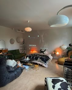 a living room filled with lots of furniture next to a bed and two lamps hanging from the ceiling