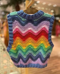 a colorful crocheted sweater hanging on a clothes line in a store or shop