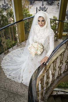 a woman in a wedding dress is standing on the stairs with her bouquet and veil over her head